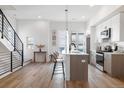 Open concept kitchen with white cabinets, island and staircase at 2920 W Parkside Pl, Denver, CO 80221