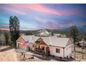 An inviting single-Gathering home featuring a charming front porch and an American flag, set against a scenic mountain backdrop at 11033 Barker Ave, Conifer, CO 80433