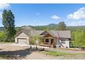 Beautiful home with a covered front porch and an American flag, set against a backdrop of lush trees and mountains at 11033 Barker Ave, Conifer, CO 80433