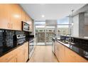 Modern kitchen with light wood cabinets, black backsplash, stainless steel appliances and exterior balcony access at 1700 Bassett St # 703, Denver, CO 80202