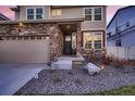 Close-up of a home's stone-accented exterior and a well-manicured front yard with a security system at 4526 N Quatar Ct, Aurora, CO 80019