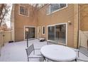 Small backyard patio area covered in snow with a table and chairs at 9573 E Kansas Cir # 57, Denver, CO 80247