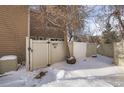 View of a snow covered backyard with a gate and a tree at 9573 E Kansas Cir # 57, Denver, CO 80247