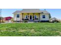 Inviting one-story home with a covered front porch and lush green lawn at 10691 County Road 23, Fort Lupton, CO 80621