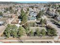 A high aerial view of the home and neighborhood with mature trees, and a white fenced yard at 335 Jefferson St, Monument, CO 80132