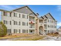 Condo exterior showing the private balcony, gray siding, and brick entry stairs at 15700 E Jamison Dr # 6-201, Englewood, CO 80112