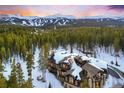 Breathtaking aerial view of a snow-covered luxury home nestled among lush evergreen trees and mountain peaks at 327 Peerless Dr, Breckenridge, CO 80424