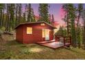 Red cabin with a cozy deck set against a backdrop of a colorful sky at dusk at 154 Apache Rd, Evergreen, CO 80439