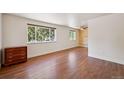 Bright bedroom with hardwood floors and decorative wood accent wall, complemented by a window and dresser at 3150 W Mexico Ave, Denver, CO 80219