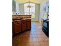Bright kitchen area featuring tile flooring, wooden cabinets, and a sink under a high, arched window at 7440 S Blackhawk St # 207, Englewood, CO 80112