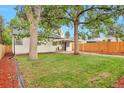 Serene backyard featuring mature trees, a well-manicured lawn, and a privacy fence at 1325 Dayton St, Aurora, CO 80010