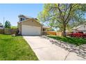 Well-maintained home featuring a spacious driveway, mature trees, and a neatly manicured lawn at 4860 E 120Th Pl, Thornton, CO 80241