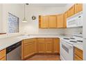 Functional kitchen featuring bright cabinets, white appliances, plenty of counter space, and hardwood floors at 10784 W 63Rd Pl # 205, Arvada, CO 80004