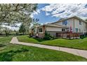 View of the exterior featuring stone facade and a lovely wooden deck with green lawn at 3354 S Flower St # 52, Lakewood, CO 80227