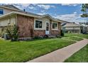 Charming exterior featuring a stone facade, healthy green lawn, and a sidewalk leading to the main entrance at 3354 S Flower St # 52, Lakewood, CO 80227