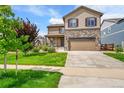 Two story home featuring a stone facade and manicured lawn at 7465 E 157Th Pl, Thornton, CO 80602