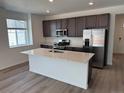 Modern kitchen with stainless steel appliances, an island with countertop and dark cabinets at 2668 Simpson Ln, Erie, CO 80026