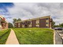 Low-angle exterior view of a brick apartment complex with a lush lawn and inviting sidewalk at 3653 S Sheridan Blvd # 16, Denver, CO 80235