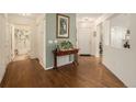 Inviting foyer with hardwood floors, light green accent wall, and a view of the front door and bathroom at 7683 S Biloxi Way, Aurora, CO 80016