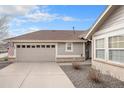 View of the home's garage, driveway, and a peek at the covered entryway on a sunny day at 7683 S Biloxi Way, Aurora, CO 80016