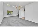 Spacious living room with tall ceilings, plush gray carpet, and a chandelier for ambient lighting at 11963 Dahlia Dr, Thornton, CO 80233