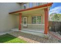 Covered porch with white railing and red accents, creating a welcoming entrance to the home at 11963 Dahlia Dr, Thornton, CO 80233