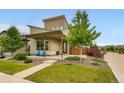 Contemporary-style home with a covered porch and blue chairs, surrounded by lush landscaping and modern design elements at 9636 Bennett Peak St, Littleton, CO 80125