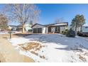 Front view of a ranch style home with a two car garage, and snowy yard at 2538 S Dover Way, Lakewood, CO 80227