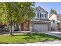 Charming two-story home with a brick facade, inviting porch swing, well-kept lawn, and a two-car garage at 14828 E 118Th Pl, Commerce City, CO 80603