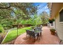Relaxing backyard patio with outdoor dining set, brick pavers, and lush greenery at 1583 Sunset Ridge Rd, Highlands Ranch, CO 80126