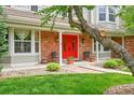 Inviting front porch with double red doors, brick accents, and manicured landscaping at 1583 Sunset Ridge Rd, Highlands Ranch, CO 80126