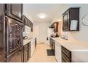 Functional kitchen with dark wood cabinets, white appliances, and ample counter space at 14937 E Security Way, Aurora, CO 80011