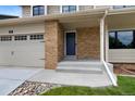Inviting front entrance with brick accents, concrete steps, a blue door, and an attached two car garage at 23 Honey Locust, Littleton, CO 80127
