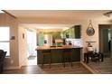Eat-in kitchen with green cabinets, center island, breakfast bar, and stainless steel appliances at 2625 S Xanadu Way # E, Aurora, CO 80014