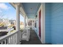 Inviting covered porch with classic white columns and a pop of color from the red front door at 3465 Beeler Ct, Denver, CO 80238