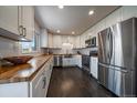 Bright kitchen with white cabinets, butcher block countertops, stainless steel appliances and hardwood flooring at 6026 Iris Way, Arvada, CO 80004