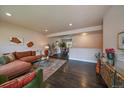 Cozy living room with dark hardwood floors, area rug, and direct access to the dining area at 6026 Iris Way, Arvada, CO 80004