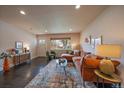 Comfortable living room featuring hardwood floors, large window, and a stylish orange sectional sofa at 6026 Iris Way, Arvada, CO 80004