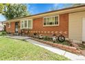 Close-up of a well-kept brick house with a charming front patio and colorful flower beds at 8660 De Soto St, Denver, CO 80229