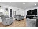 Bright living room featuring neutral walls, wood floors, and comfortable seating with a large tv at 8660 De Soto St, Denver, CO 80229
