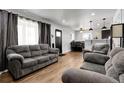 Open living space with gray couches, wood floors, and a view into dining area at 8660 De Soto St, Denver, CO 80229