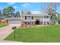 Charming home with a manicured lawn, brick accents, and attached garage offering curb appeal at 3785 S Benton Way, Denver, CO 80235