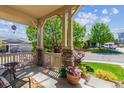 Inviting covered front porch with stone pillars, offering a cozy outdoor seating area at 10448 Kicking Horse Dr, Littleton, CO 80125