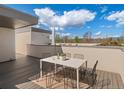 Outdoor rooftop patio features table, chairs, and views of blue sky and distant mountains at 4917 Lowell Blvd # 105, Denver, CO 80221