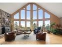 Bright living room boasts soaring windows, hardwood floors, stone fireplace and ample seating at 13452 Riley Peak Rd, Conifer, CO 80433