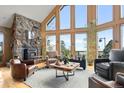 Bright living room boasts soaring windows, hardwood floors, stone fireplace and ample seating at 13452 Riley Peak Rd, Conifer, CO 80433