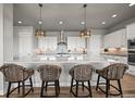 Modern kitchen with a large island, pendant lighting, and stylish bar stools at 3293 Offbeaten Pl, Castle Rock, CO 80108