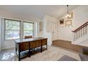 Bright entryway featuring a wooden desk, staircase, and large windows overlooking a tree-filled front yard at 8043 S Zephyr St, Littleton, CO 80128