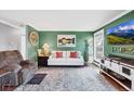 Cozy living room features green walls, stylish furniture, decor, and wood floors at 18200 E Asbury Pl, Aurora, CO 80013