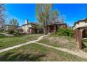 Quaint brick house with a traditional porch, surrounded by a grassy yard and mature trees at 451 Harrison St, Denver, CO 80206
